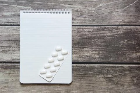 Notepad with a blank white sheet in a checker paper with pills in a blister l Foto stock
