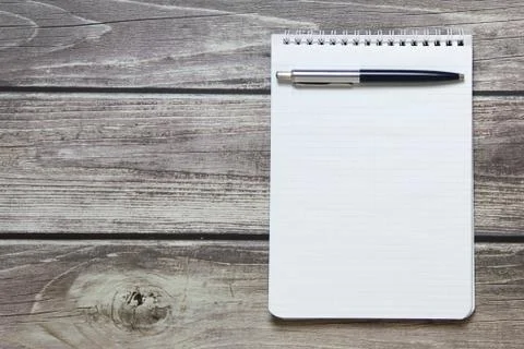 Notepad with a blank white sheet in a checker paper with ball pen lies on the Stock Photos