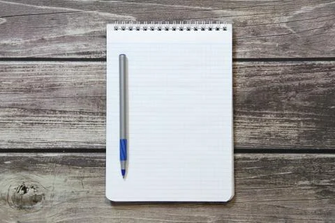 Notepad with a blank white sheet in a checker paper with ball pen lies on the Stock Photos