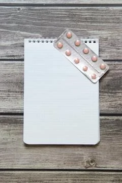Notepad with a blank white sheet in a checker paper with pills in a blister l Stock Photos