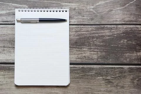 Notepad with a blank white sheet in a checker paper with ball pen lies on the Stock Photos