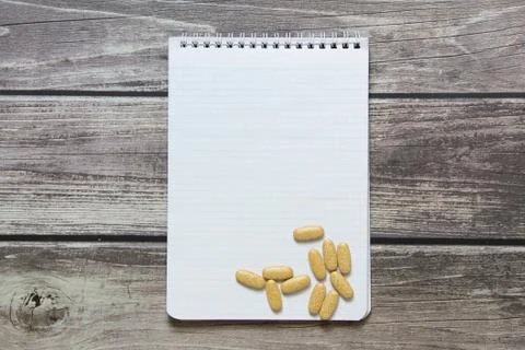 Notepad with a blank white sheet in a checker paper with pills lies on the ba Foto stock