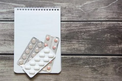 Notepad with a blank white sheet in a checker paper with pills in a blister lies Stock Photos