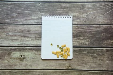 Notepad with a blank white sheet in a checker paper with pills lies on the Stock Photos