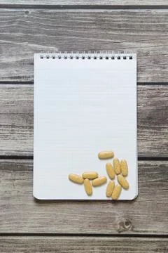 Notepad with a blank white sheet in a checker paper with pills lies on the ba Stock Photos