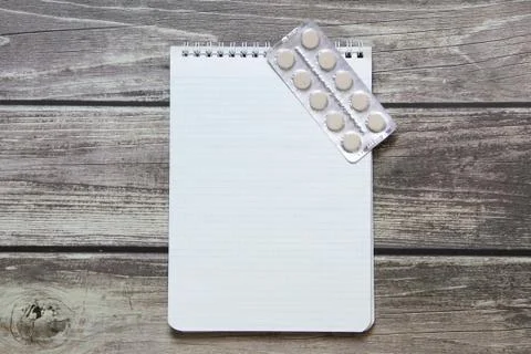 Notepad with a blank white sheet in a checker paper with pills in a blister l Foto stock