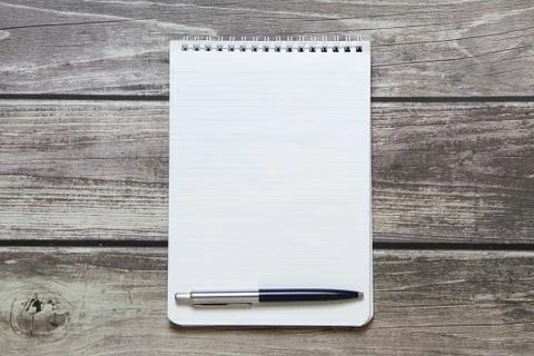 Notepad with a blank white sheet in a checker paper with ball pen lies on the Stock Photos