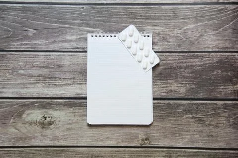 Notepad with a blank white sheet in a checker paper with pills in a blister l Foto stock