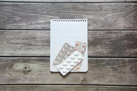 Notepad with a blank white sheet in a checker paper with pills in a blister l Stock Photos