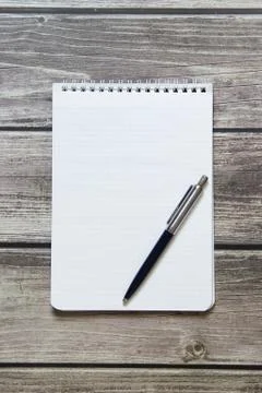 Notepad with a blank white sheet in a checker paper with ball pen lies on the Stock Photos