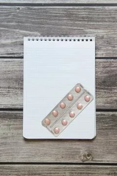 Notepad with a blank white sheet in a checker paper with pills in a blister l Stock Photos