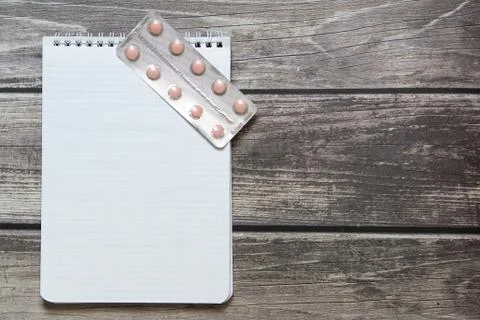 Notepad with a blank white sheet in a checker paper with pills in a blister l Stock Photos