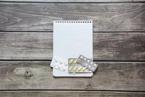 Notepad with a blank white sheet in a checker paper with pills in a blister l Stock Photos