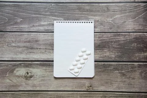 Notepad with a blank white sheet in a checker paper with pills in a blister l Stock Photos