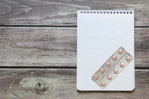 Notepad with a blank white sheet in a checker paper with pills in a blister l Stock Photos