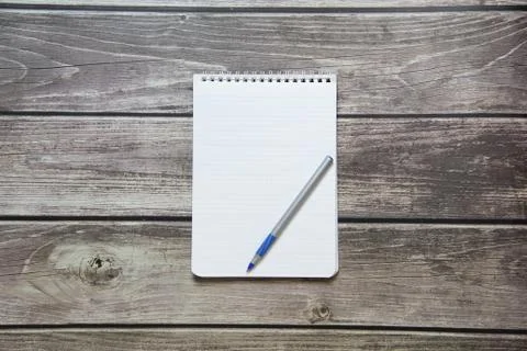 Notepad with a blank white sheet in a checker paper with ball pen lies on the Stock Photos