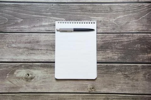 Notepad with a blank white sheet in a checker paper with ball pen lies on the Stock Photos