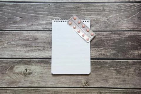 Notepad with a blank white sheet in a checker paper with pills in a blister l Stock Photos
