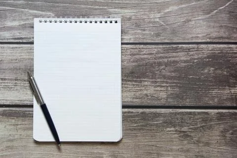 Notepad with a blank white sheet in a checker paper with ball pen lies on the Stock Photos