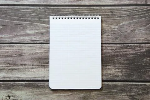 Notepad with a blank white sheet in a checker paper lies on the background of Stock Photos
