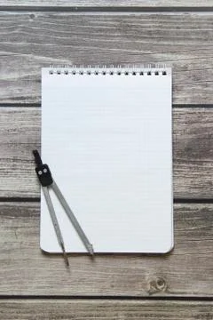 Notepad with a blank white sheet in a checker paper with compass lies on the  Stock Photos
