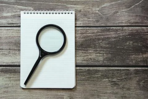 Notepad with a blank white sheet in a checker paper lies with magnifying glas Stock Photos