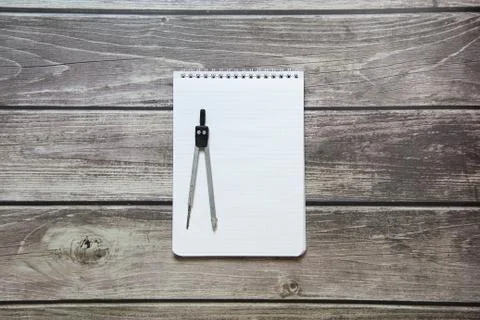 Notepad with a blank white sheet in a checker paper with compass lies on the  Stock Photos