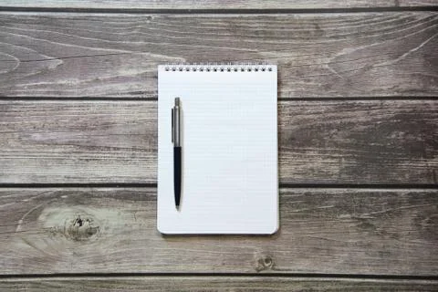 Notepad with a blank white sheet in a checker paper with ball pen lies on the Stock Photos