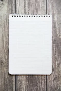 Notepad with a blank white sheet in a checker paper lies on the background of Stock Photos