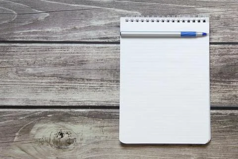 Notepad with a blank white sheet in a checker paper with ball pen lies on the Stock Photos