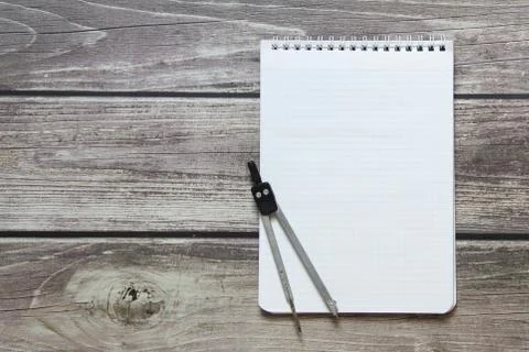 Notepad with a blank white sheet in a checker paper with compass lies on the  Stock Photos