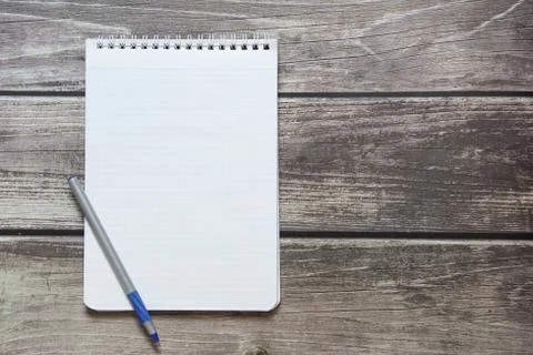 Notepad with a blank white sheet in a checker paper with ball pen lies on the Stock Photos