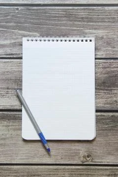 Notepad with a blank white sheet in a checker paper with ball pen lies on the Stock Photos