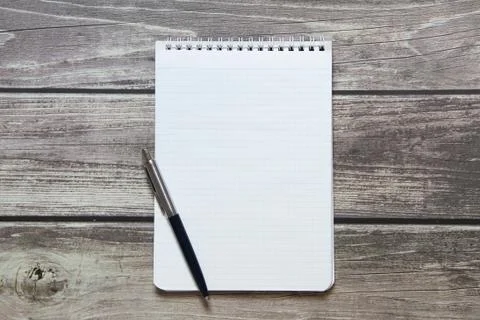 Notepad with a blank white sheet in a checker paper with ball pen lies on the Stock Photos