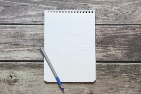 Notepad with a blank white sheet in a checker paper with ball pen lies on the Stock Photos