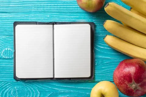Notepad on blue wooden background surrounded by fresh fruit Stock Photos