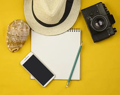 A notepad on a bright yellow background, a straw hat, a shell Stock Photos