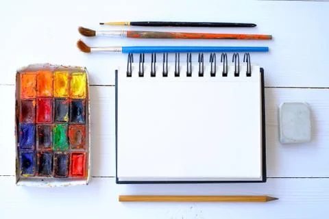 Notepad, brushes and paint on the table Stock Photos