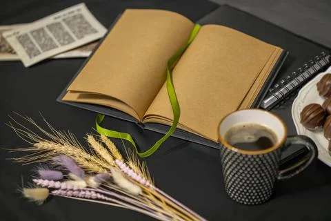 Notepad, chocolates, a cup of coffee, old flyers and spikelets on a black b.. Stock Photos