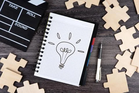 Notepad with cinematic  clapper, pen and puzzle pieces and idea symbol Foto stock