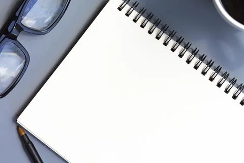 Notepad with coffee cup, reading glasses and a pen on a desk. Copy space. Stock Photos
