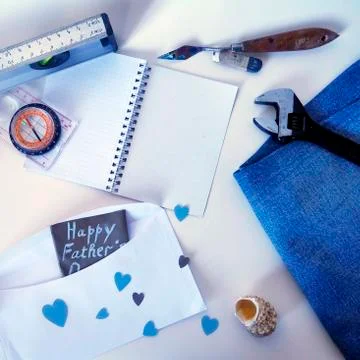 Notepad, compass, wrench, shell on denim and postcard to father's day Stock Photos