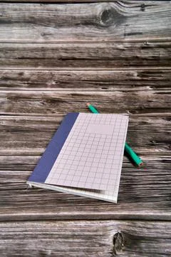 Notepad with crossed and parallel lines along with a pencil on a wooden desk. Stock Photos