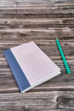 Notepad with crossed and parallel lines along with a pencil on a wooden desk. Stock Photos
