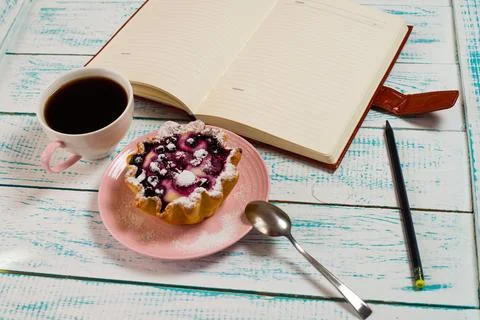 Notepad, a cup of coffee and a cake basket with berries and cottage cheese on Stock Photos