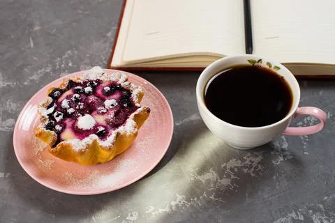 Notepad, a cup of coffee and a cake basket with berries and cottage cheese on Foto stock