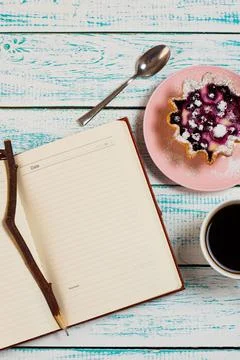 Notepad, a cup of coffee and a cake basket with berries and cottage cheese on Stock Photos