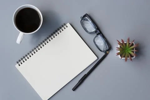Notepad with cup of coffee and reading glasses on a desk. Directly above. Stock Photos