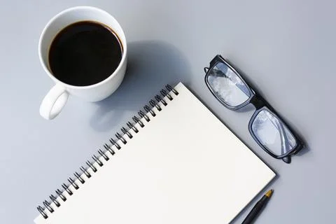 Notepad with cup of coffee and reading glasses on a desk. Directly above. Stock Photos