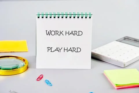 A notepad on a desk says Work Hard Play Hard. Nearby are office supplies like a Foto stock